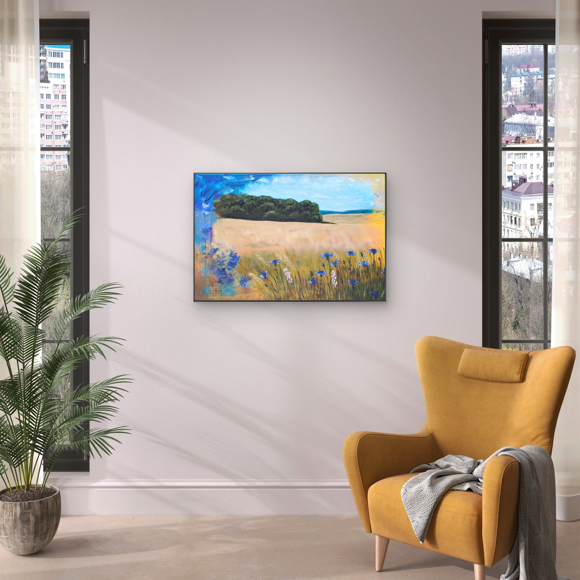 A room space with a yellow armchair and plant featuring a painting of field with cornflowers.