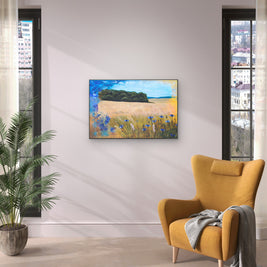 A room space with a yellow armchair and plant featuring a painting of field with cornflowers.