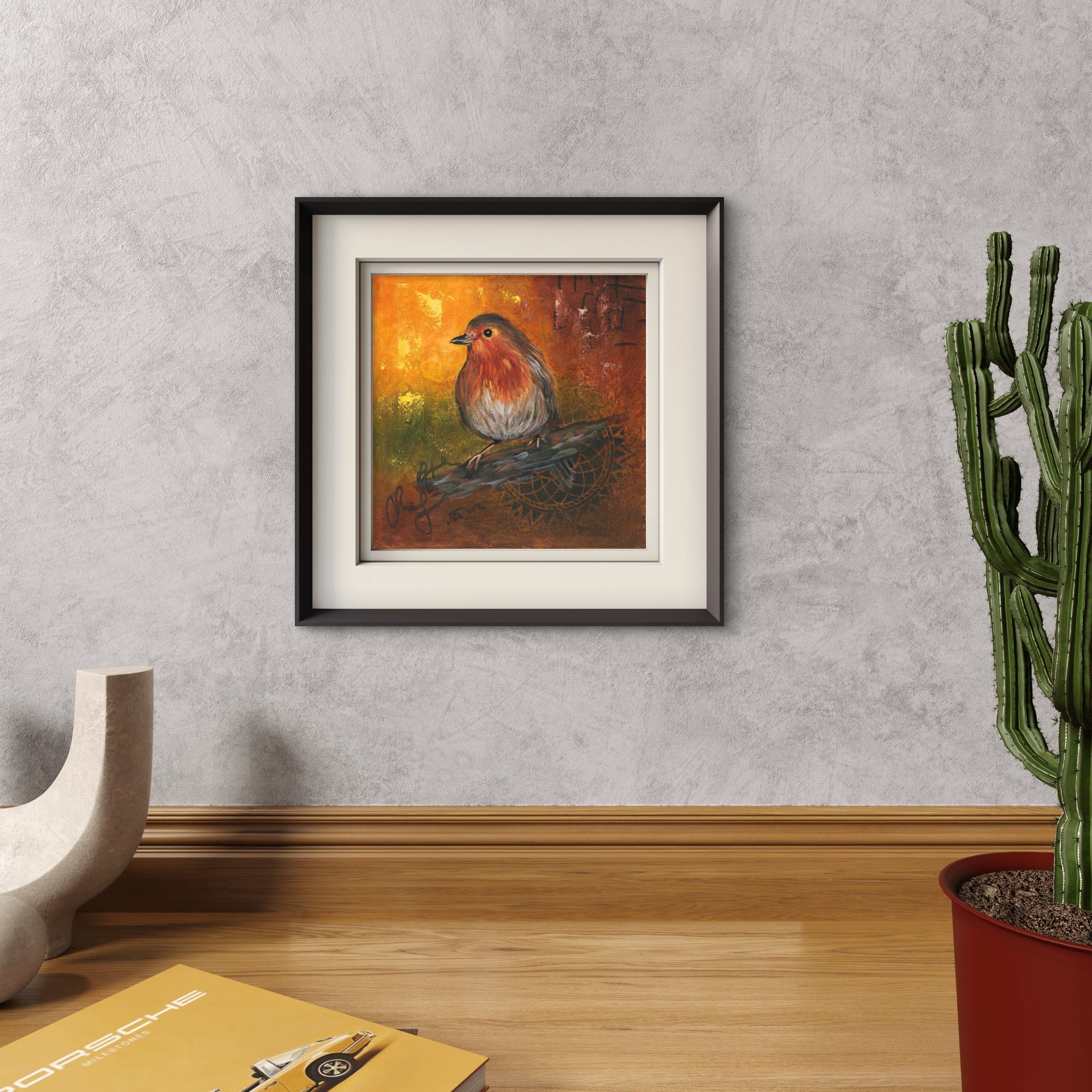 Framed Robin painting on the wall near a cactus.