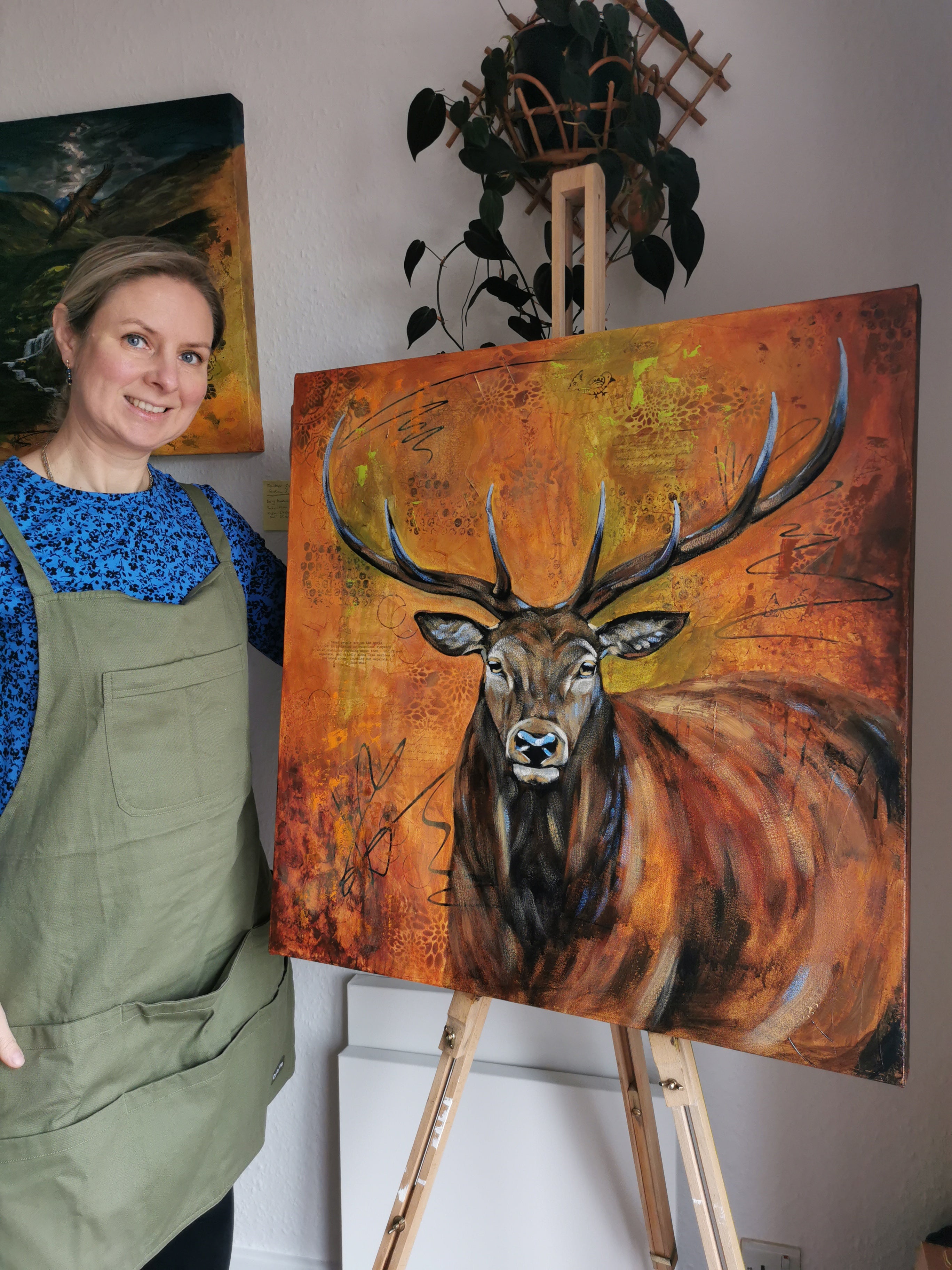 Woman standing next to a painting of a deer on an easel