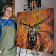Woman standing next to a painting of a deer on an easel