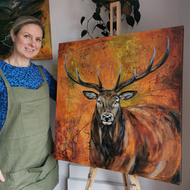 Woman standing next to a painting of a deer on an easel