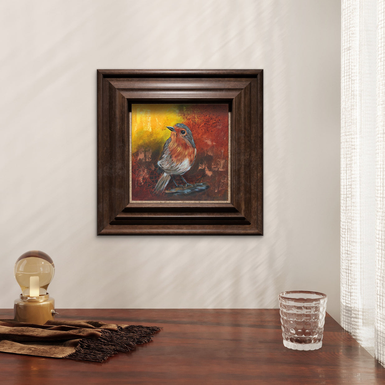 Small painting of a robin framed in a dark wooden frame hanging on a wall.