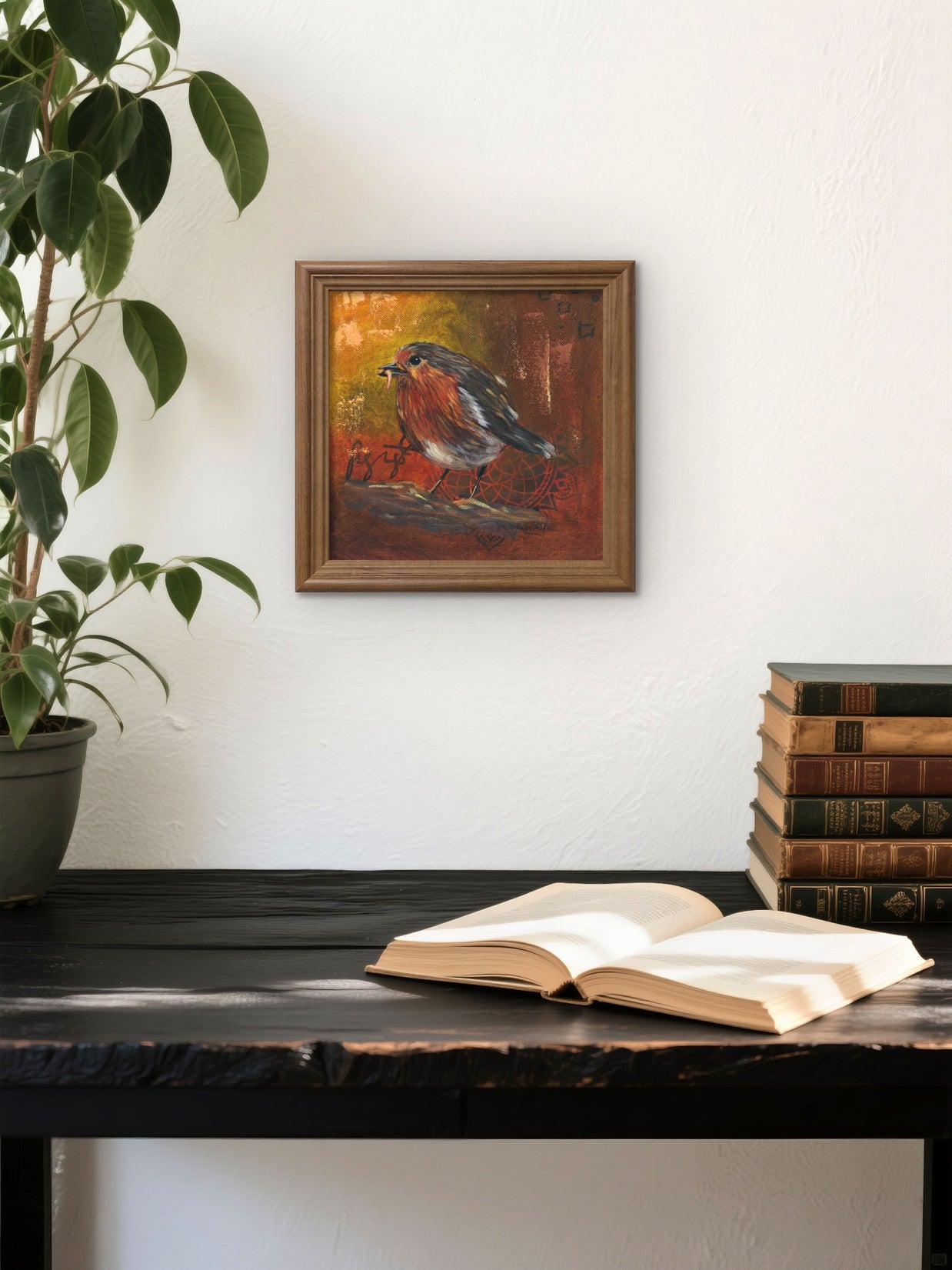 Framed painting of a feeding robin on a wall above a desk. 