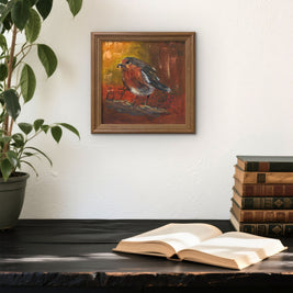 Framed painting of a feeding robin on a wall above a desk. 