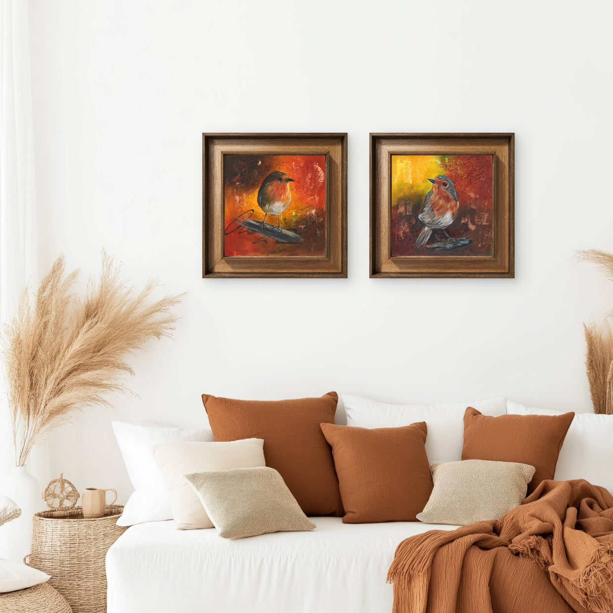 Arrangement of 2 paintings of robins on a wall above a sofa.