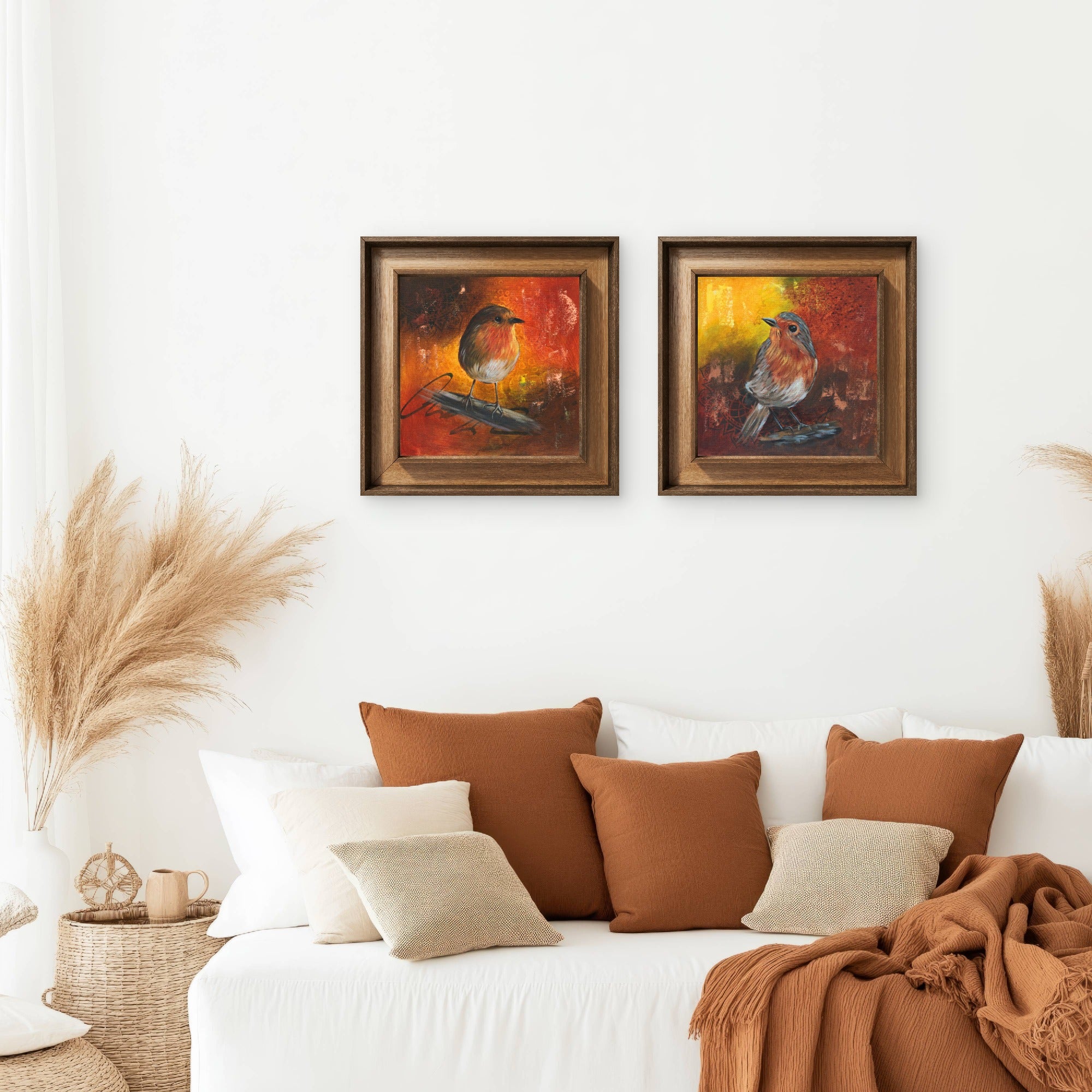 Arrangement of 2 paintings of robins on a wall above a sofa.