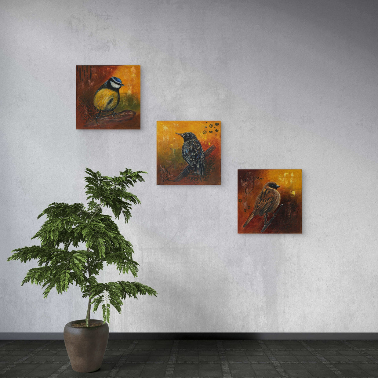 Arrangement of three small paintings on a wall with a large plant.